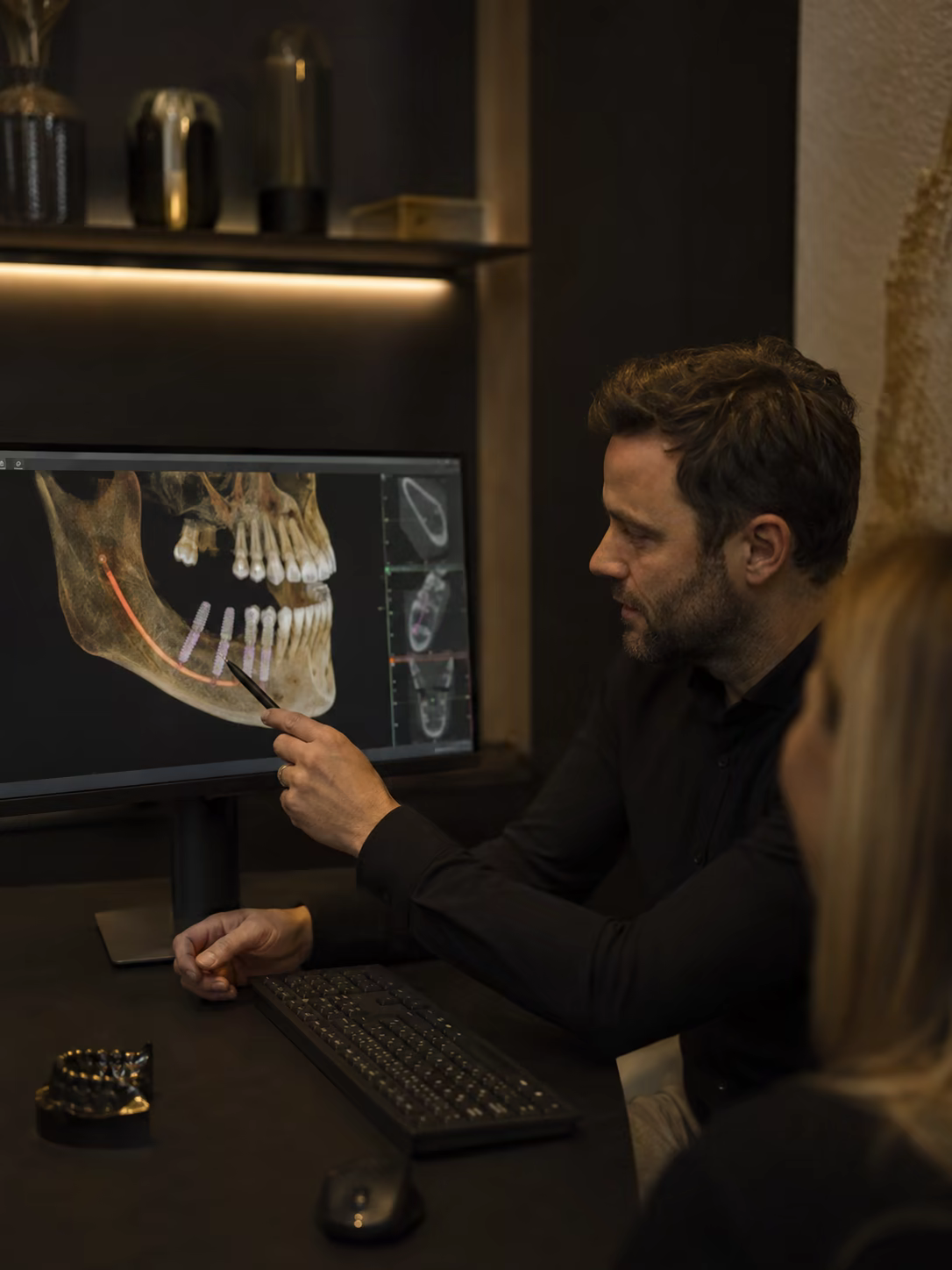 Dentist explaining a tooth replacement plan on a monitor